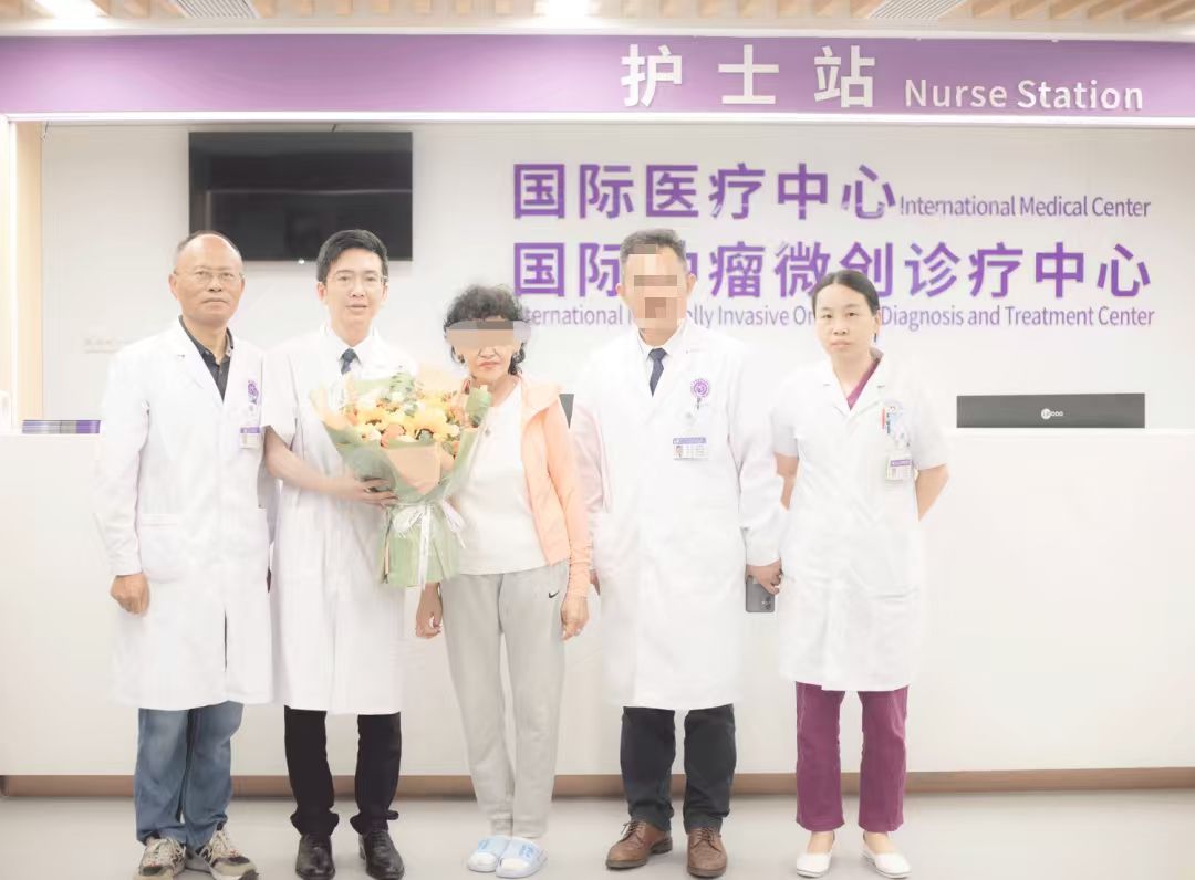 Patient with an obscured face holding flowers alongside a hospital care team