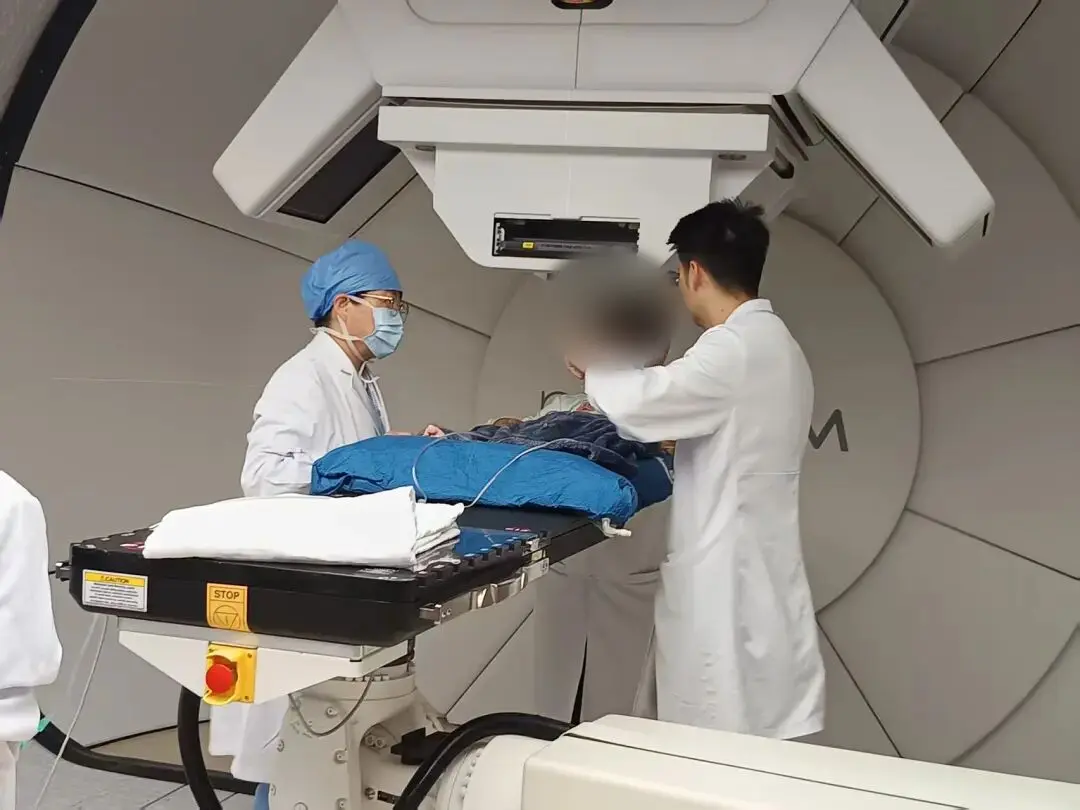 Clinical team preparing a child for treatment in a proton therapy room, with the patient face obscured