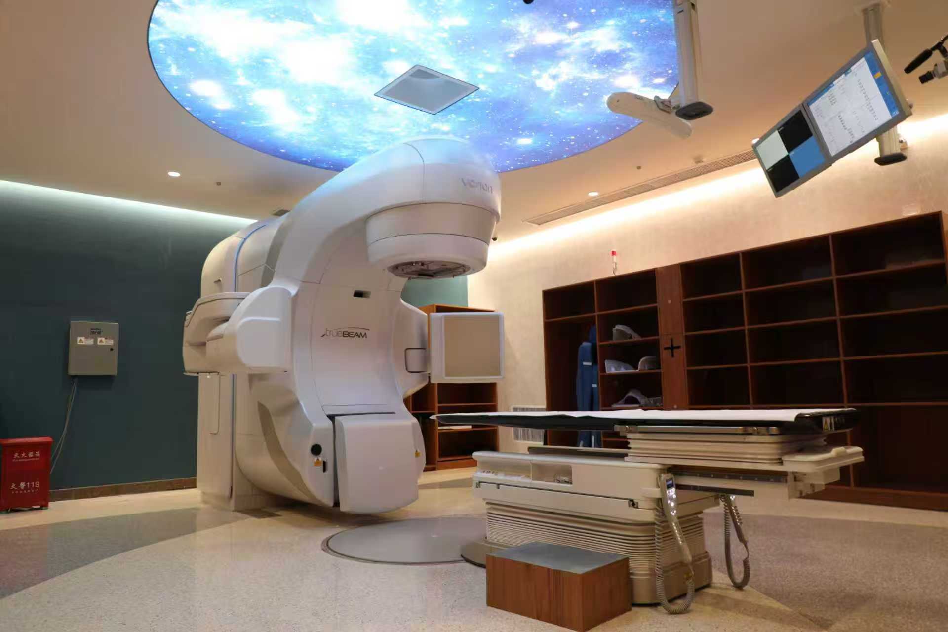 Hospital treatment equipment with a patient table and ceiling-mounted monitors